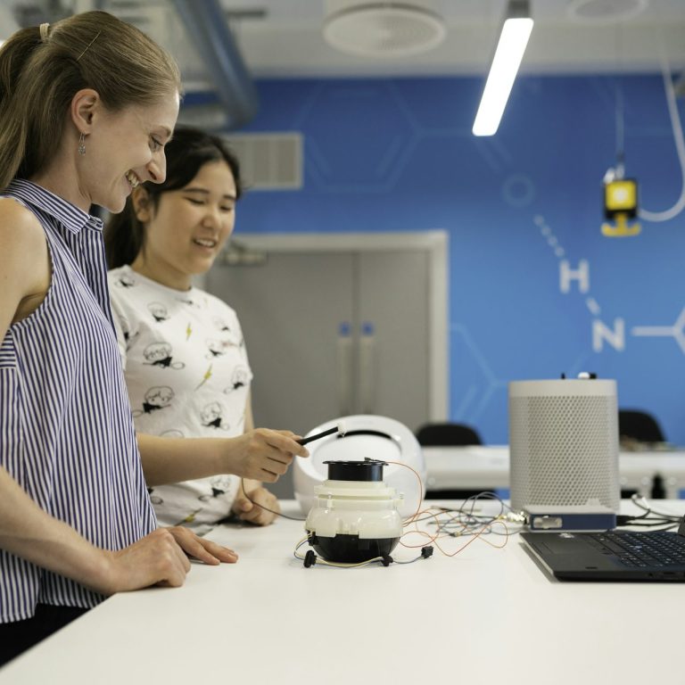 Two women collaborating on a robotics project at a modern workspace.