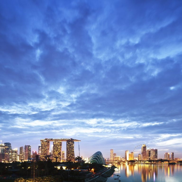 Skyline of Singapore at dusk, featuring modern buildings and a reflective water surface.